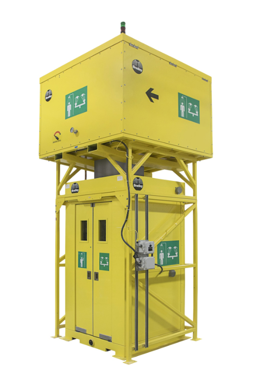 Yellow emergency shower and eye wash station with safety signage.